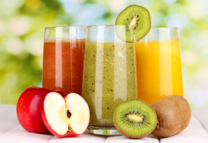 fresh fruit juices on wooden table, on green background
